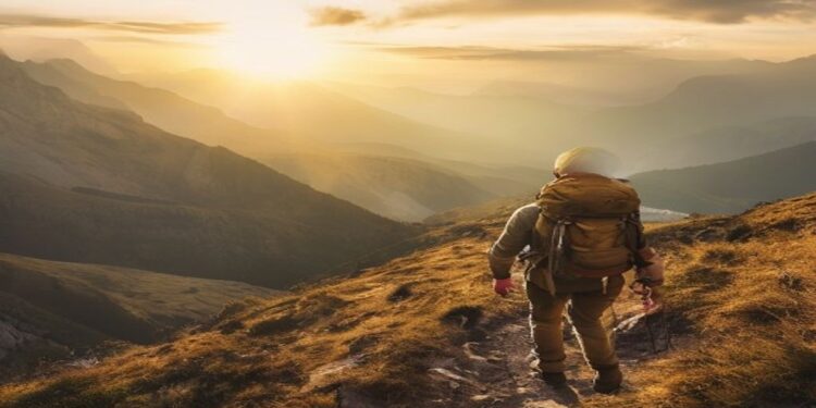 Adventure traveller hiking on a mountain trail at sunrise with a backpack