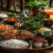 Balinese food spread with nasi campur, satay, sambal, rice, vegetables, and fresh tropical drinks on a wooden table