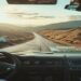 Open road through scenic hills seen from a car with a travel map and coffee on the dashboard