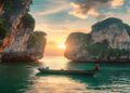 Thailand longtail boat near limestone cliffs and turquoise water at sunset