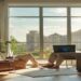 Remote worker using a laptop beside a window with luggage and travel notebook nearby
